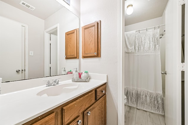 bathroom featuring toilet, curtained shower, visible vents, and vanity