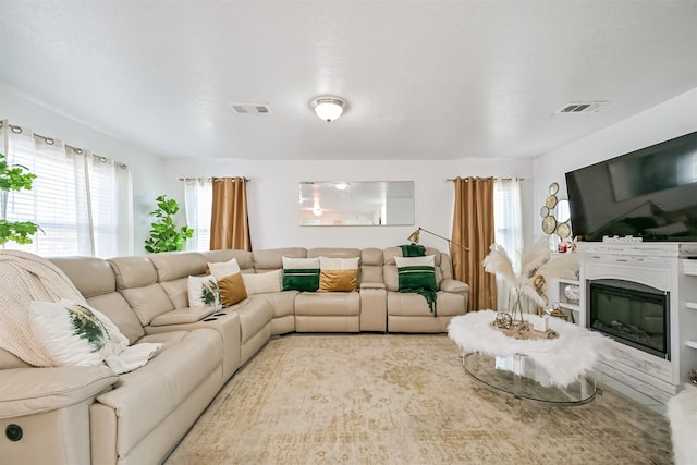 living area with a glass covered fireplace and visible vents