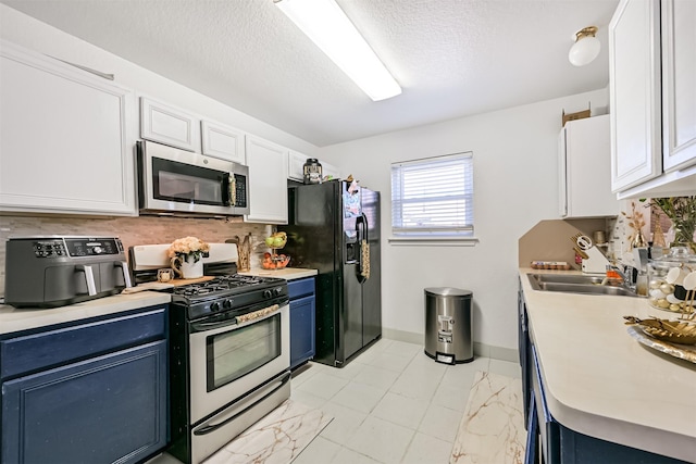 kitchen with blue cabinetry, stainless steel appliances, backsplash, and light countertops