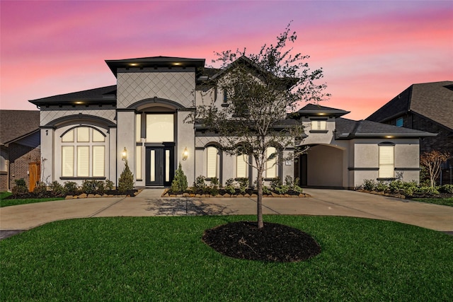 french country inspired facade with stucco siding, curved driveway, and a front yard