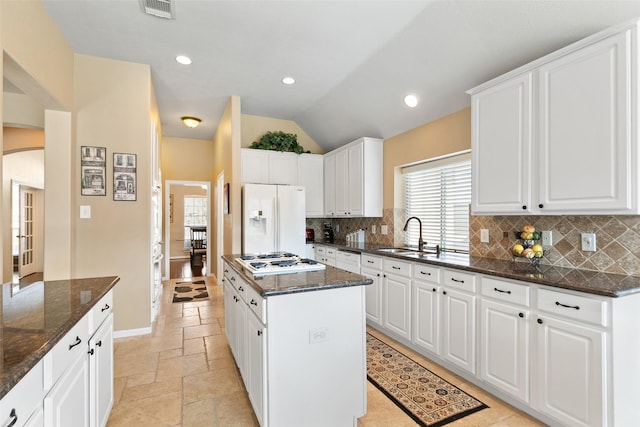 kitchen with arched walkways, stone tile floors, white appliances, a sink, and visible vents