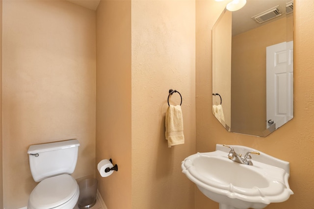 half bathroom with toilet, visible vents, and a sink