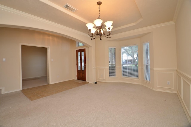 spare room featuring a raised ceiling, a decorative wall, a notable chandelier, and light carpet