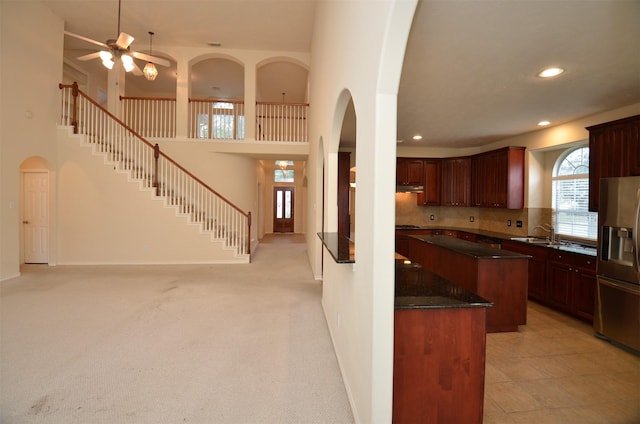 kitchen with recessed lighting, stainless steel fridge with ice dispenser, arched walkways, decorative backsplash, and a towering ceiling