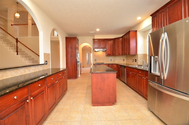 kitchen featuring a sink, tasteful backsplash, a center island, appliances with stainless steel finishes, and dark brown cabinets