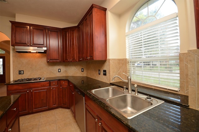 kitchen with under cabinet range hood, a sink, appliances with stainless steel finishes, light tile patterned floors, and decorative backsplash