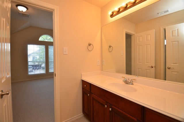 bathroom with visible vents, lofted ceiling, baseboards, and vanity