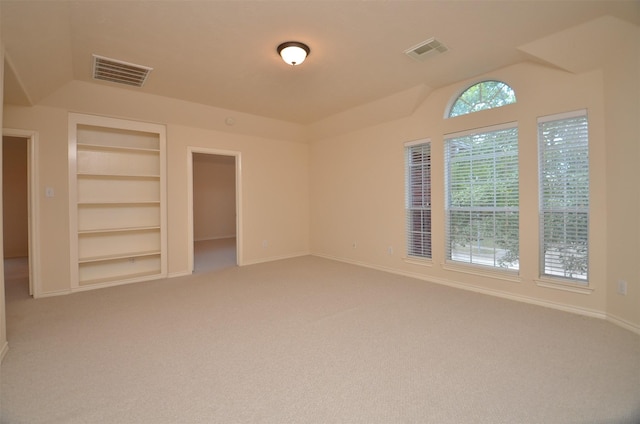 unfurnished room featuring built in features, light colored carpet, visible vents, and baseboards