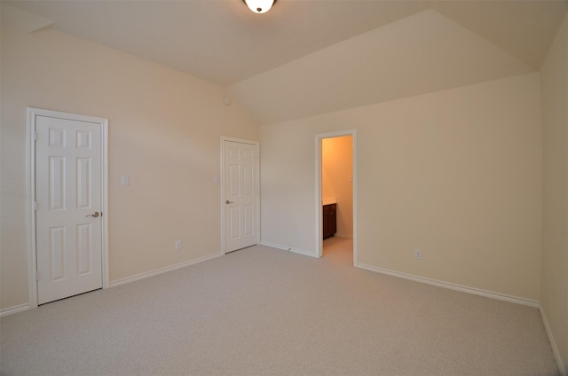 unfurnished bedroom featuring light colored carpet, baseboards, and lofted ceiling