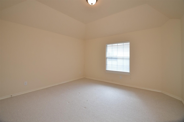 carpeted spare room with baseboards and vaulted ceiling