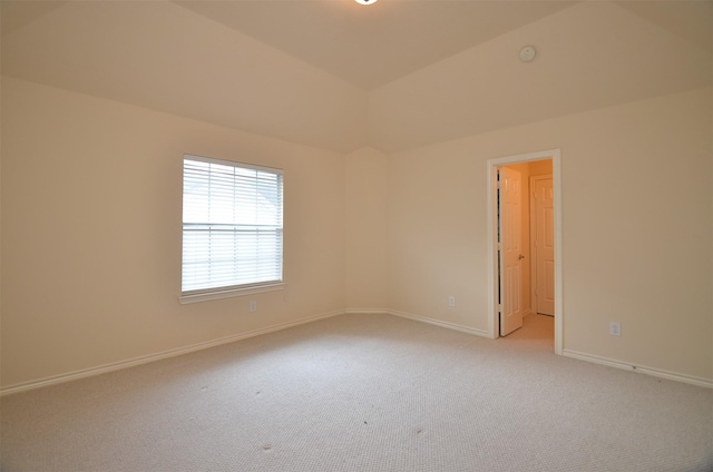 empty room with light carpet, baseboards, and lofted ceiling