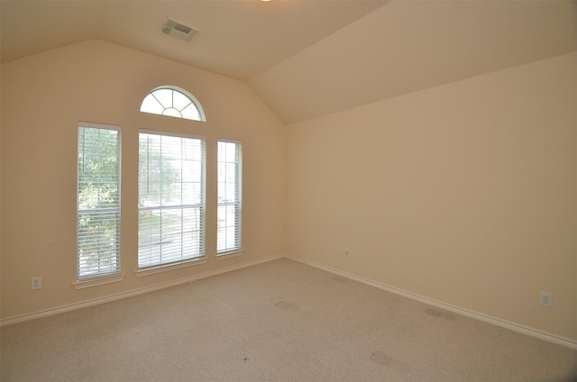 empty room with lofted ceiling, baseboards, visible vents, and light carpet