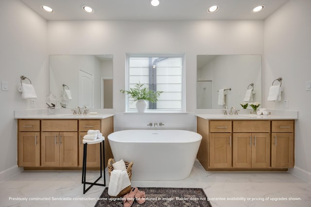 full bath with a freestanding bath, marble finish floor, a sink, and recessed lighting