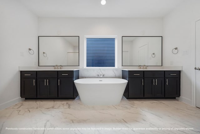bathroom with a sink, marble finish floor, two vanities, and a soaking tub