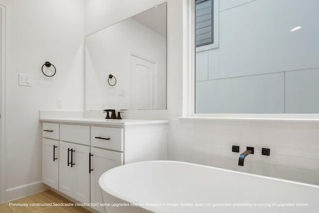 full bathroom featuring a freestanding bath, vanity, and wood finished floors