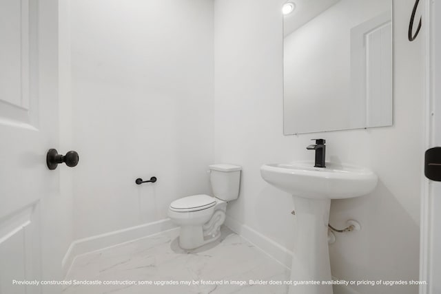 half bathroom featuring toilet, marble finish floor, and baseboards