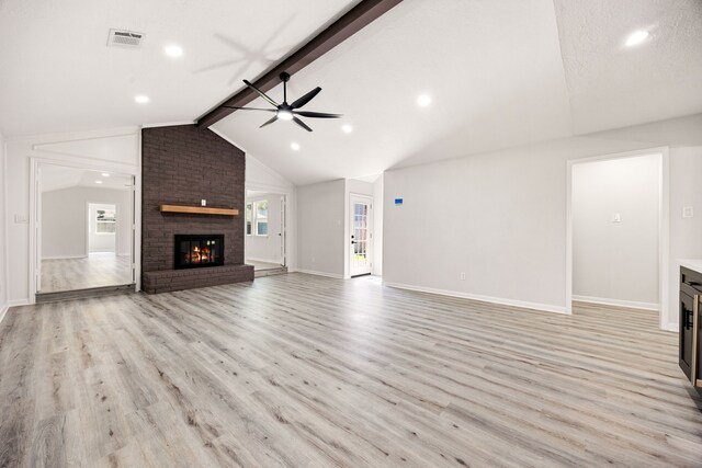 unfurnished living room featuring lofted ceiling with beams, light wood-style flooring, a ceiling fan, visible vents, and a brick fireplace