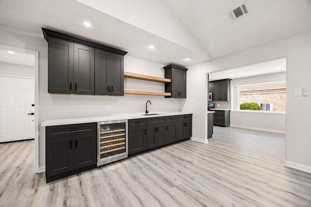 kitchen featuring beverage cooler, a sink, visible vents, light wood-type flooring, and open shelves