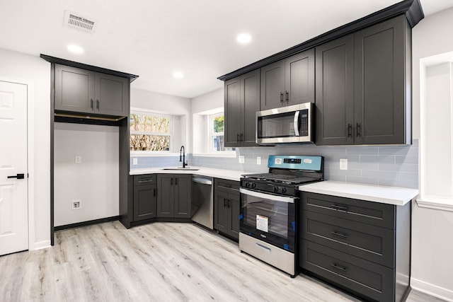 kitchen with tasteful backsplash, visible vents, appliances with stainless steel finishes, and light wood finished floors