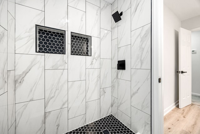 full bathroom with baseboards, tiled shower, and wood finished floors