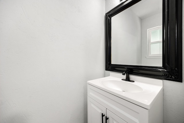 bathroom with a textured wall and vanity