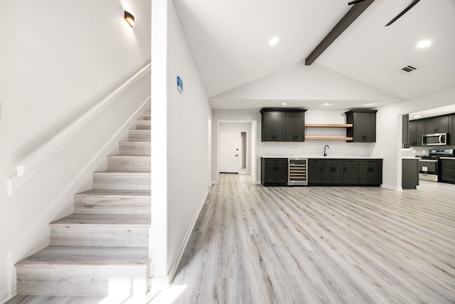 interior space featuring wine cooler, light wood finished floors, open shelves, stainless steel appliances, and a sink