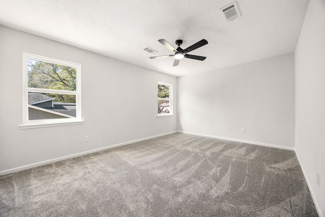 spare room featuring carpet floors, baseboards, visible vents, and a textured ceiling