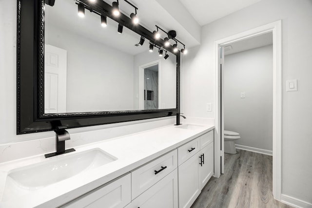 full bathroom featuring double vanity, a sink, toilet, and wood finished floors