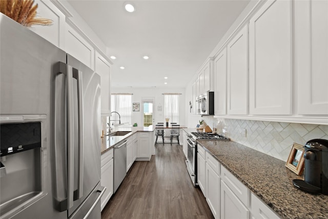 kitchen featuring tasteful backsplash, dark wood finished floors, white cabinets, appliances with stainless steel finishes, and a sink