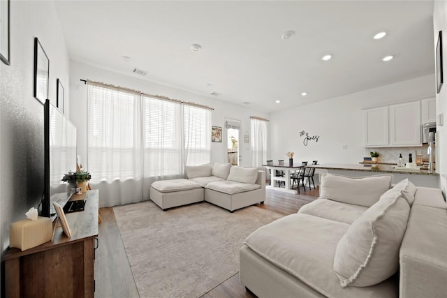 living room with light wood-style floors, visible vents, and recessed lighting