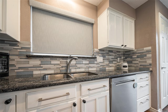 kitchen featuring dark stone counters, white cabinets, backsplash, a sink, and stainless steel dishwasher