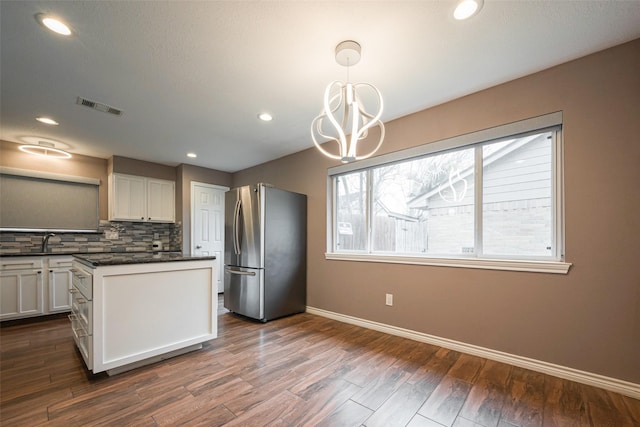 kitchen featuring dark wood finished floors, tasteful backsplash, visible vents, freestanding refrigerator, and white cabinets