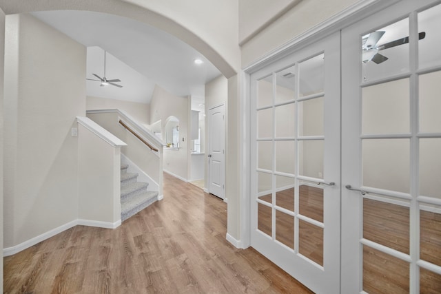 entrance foyer featuring arched walkways, wood finished floors, a ceiling fan, and baseboards