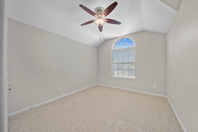 carpeted spare room with lofted ceiling, a ceiling fan, and baseboards