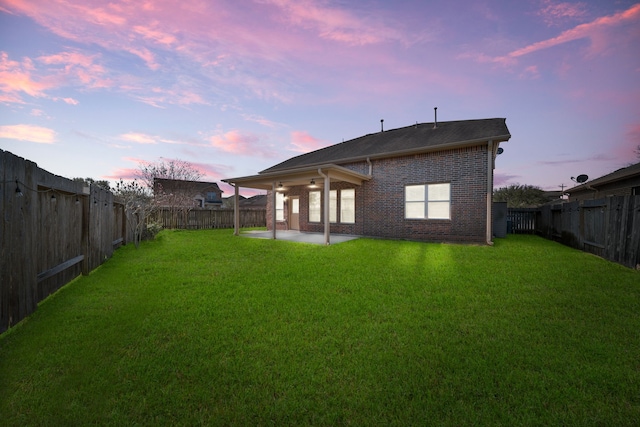 rear view of property with a patio area, a fenced backyard, a yard, and brick siding