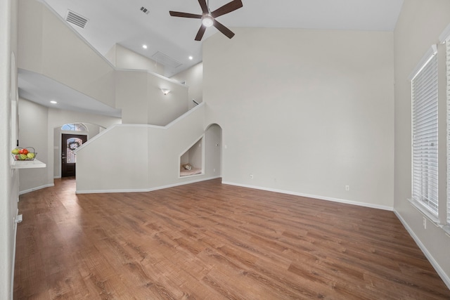 unfurnished living room featuring arched walkways, wood finished floors, visible vents, and a ceiling fan