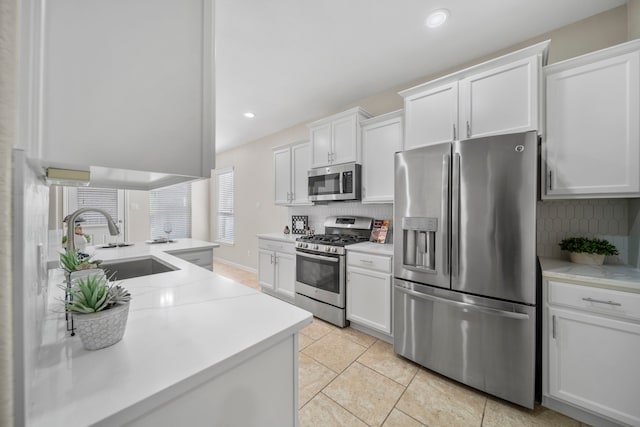 kitchen featuring light countertops, appliances with stainless steel finishes, a sink, and decorative backsplash