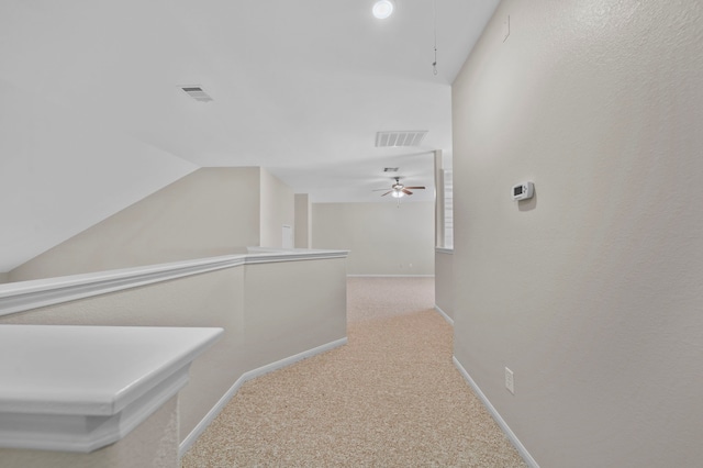 hallway with attic access, lofted ceiling, visible vents, and carpet flooring