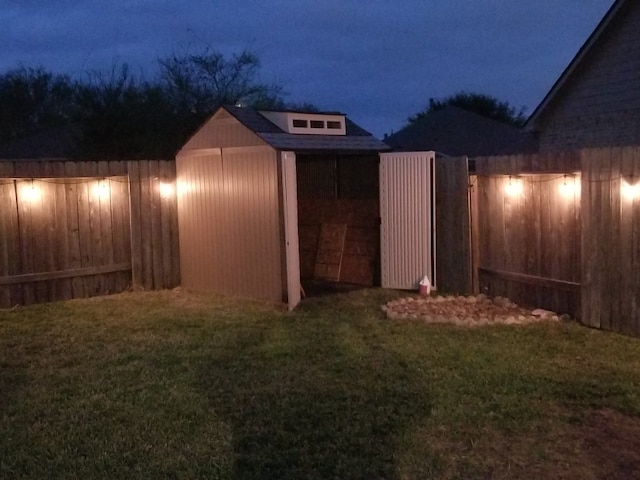 yard at twilight featuring fence and an outdoor structure