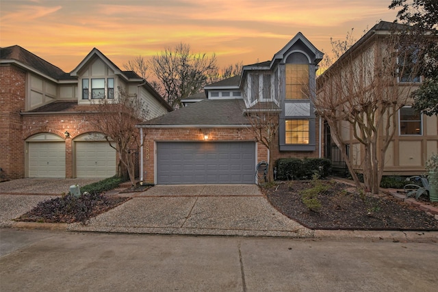 view of front of property with a shingled roof, concrete driveway, and brick siding