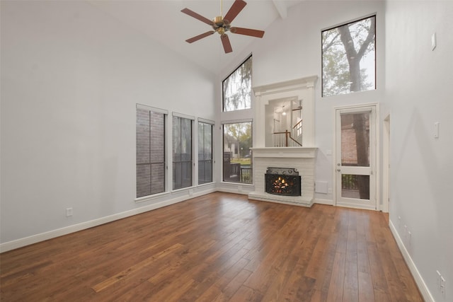 unfurnished living room featuring high vaulted ceiling, a fireplace, a ceiling fan, baseboards, and wood-type flooring