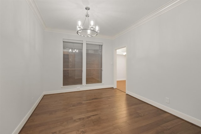 spare room with wood-type flooring, crown molding, baseboards, and an inviting chandelier