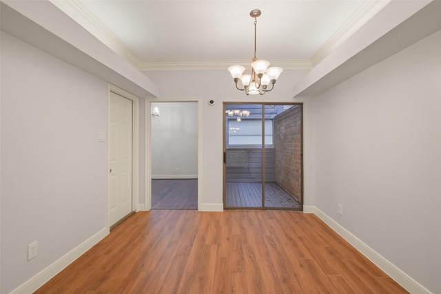 unfurnished dining area featuring a chandelier, ornamental molding, baseboards, and wood finished floors