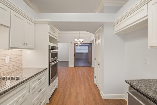 kitchen featuring crown molding, a notable chandelier, backsplash, appliances with stainless steel finishes, and light wood-style floors