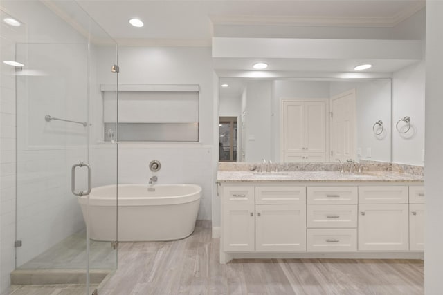 bathroom featuring double vanity, a stall shower, ornamental molding, and a sink