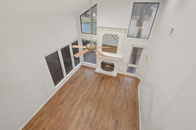 living area with wood finished floors, visible vents, baseboards, a ceiling fan, and a brick fireplace