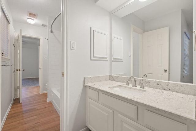 full bath featuring wood finished floors, vanity, visible vents, baseboards, and shower / bathing tub combination