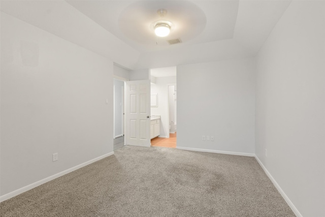 empty room featuring baseboards, a tray ceiling, visible vents, and light colored carpet