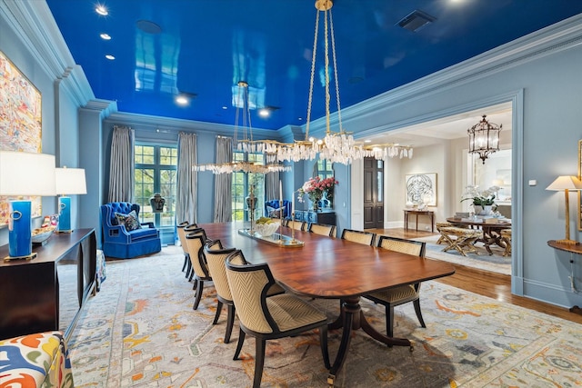 dining room with baseboards, visible vents, wood finished floors, and ornamental molding