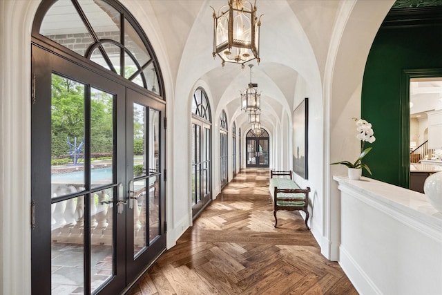 hallway featuring arched walkways, french doors, lofted ceiling, and a notable chandelier